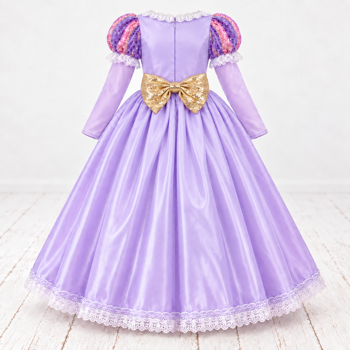 Back view of a lavender girls’ princess costume with patterned puff sleeves, long sleeves, a centre zip, full satin-look skirt, white lace-trimmed hem and a large gold sequin bow at the waist.