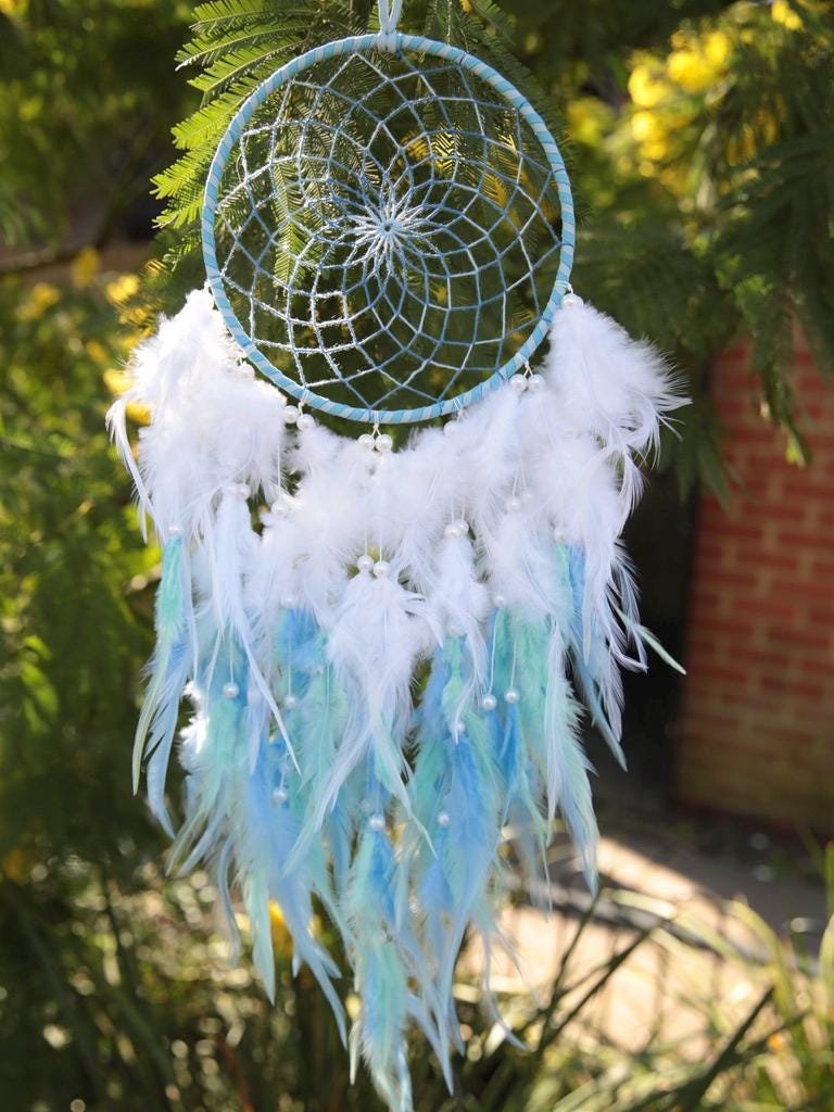 Blue hand woven dreamcatcher with  pink and white fluffy feathers decorated with beads. Welcome to new home gift, bedroom decor